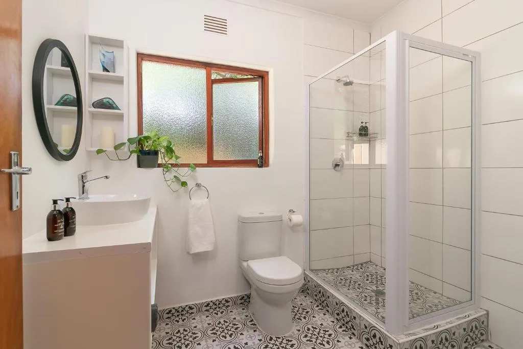 Modern bathroom with walk-in shower, vanity sink, and decorative floor tiles