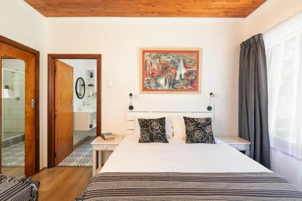 Bright bedroom with queen bed, wooden ceiling, and ensuite bathroom visible