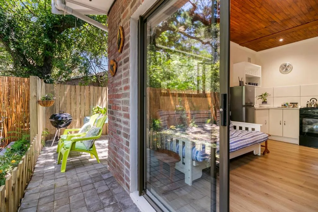Sunny outdoor patio with green chair, wooden fence, and garden access