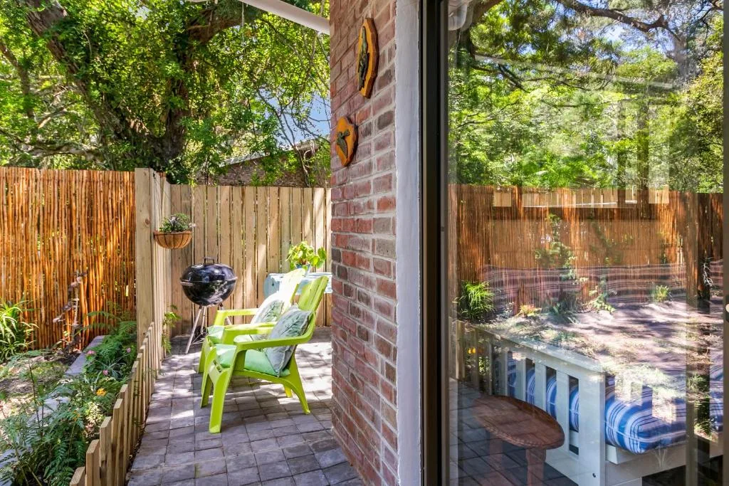 Shaded patio with green chairs, braai grill, and timber fence surround