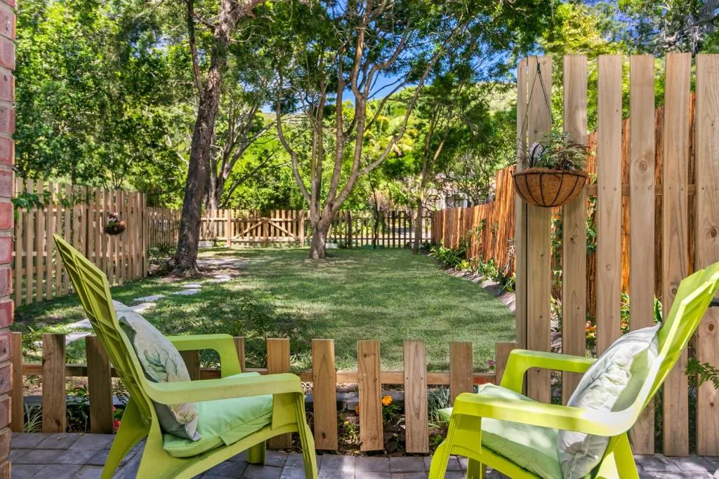 Backyard garden with bright green chairs and mature shade trees