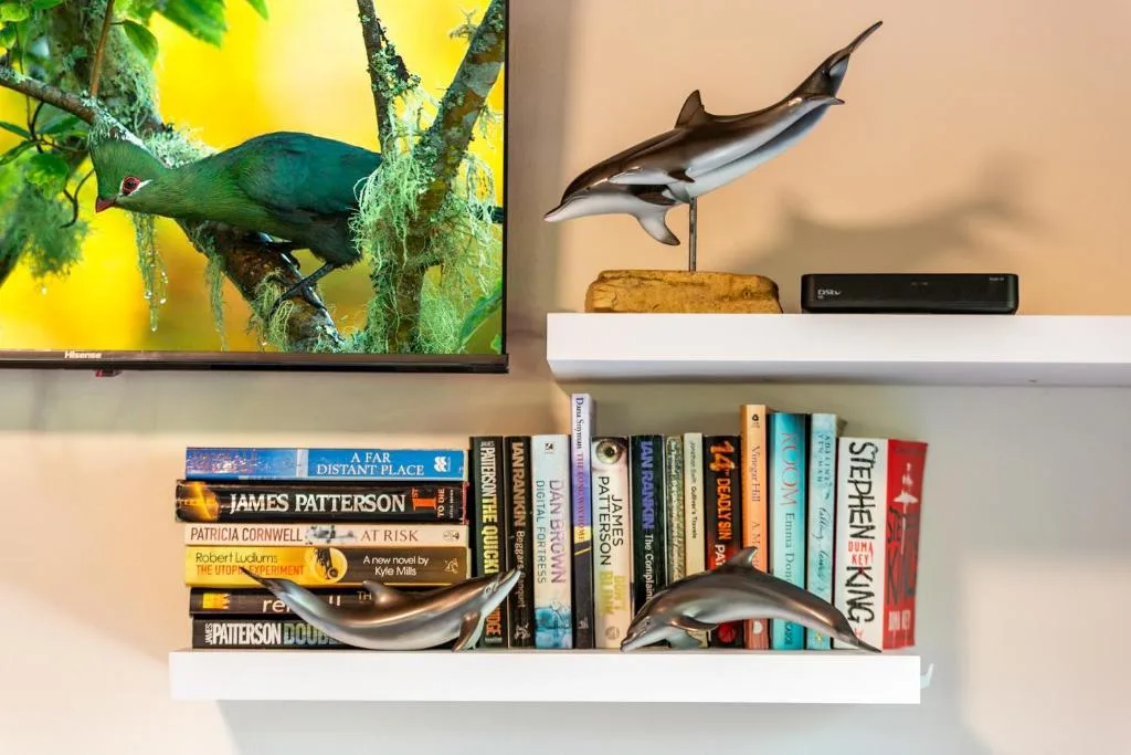 Shelving with books, shark figurines, and wall-mounted bird artwork decoration