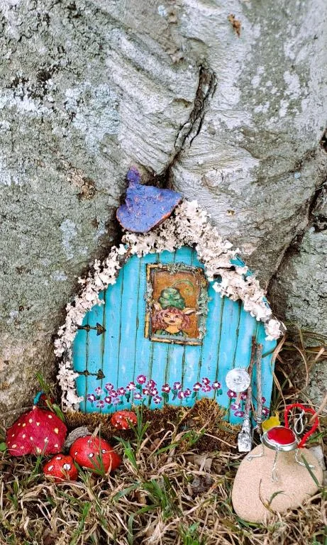Whimsical fairy door decoration with turquoise painted wood and flowers