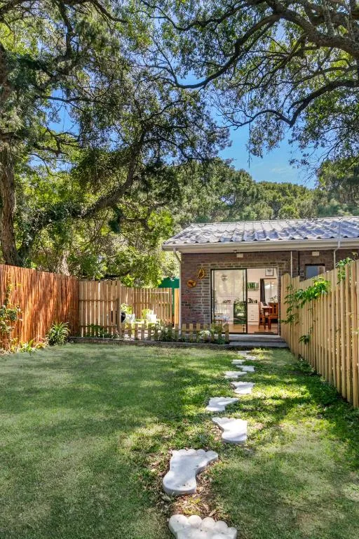 Modern cottage with wooden fence and lush garden under mature trees