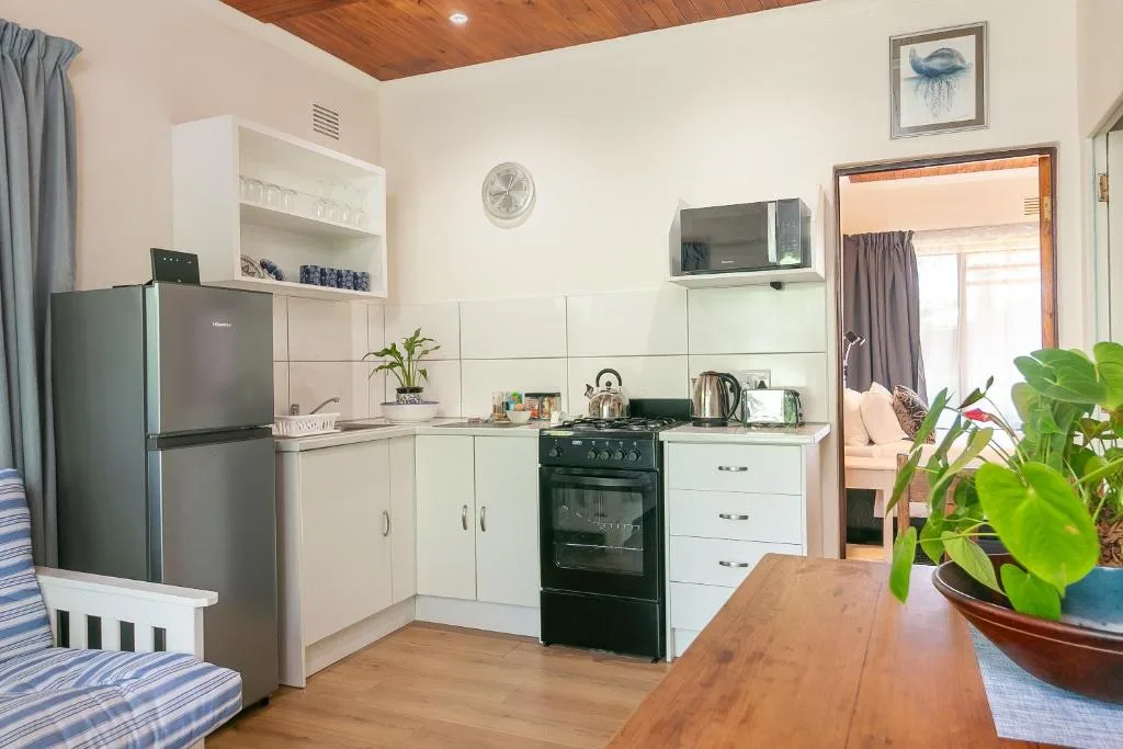 Open-plan kitchen with cream cabinetry, black range cooker, stainless steel fridge, and wooden ceiling