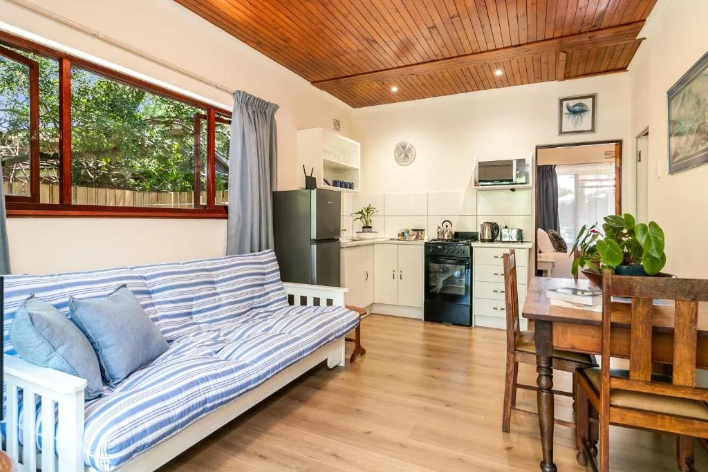 Open-plan lounge with striped sofa, kitchen area, and wooden ceiling