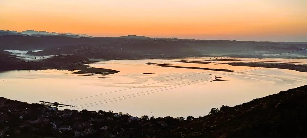 Sunset over Knysna Lagoon with golden light reflecting on water and mountains