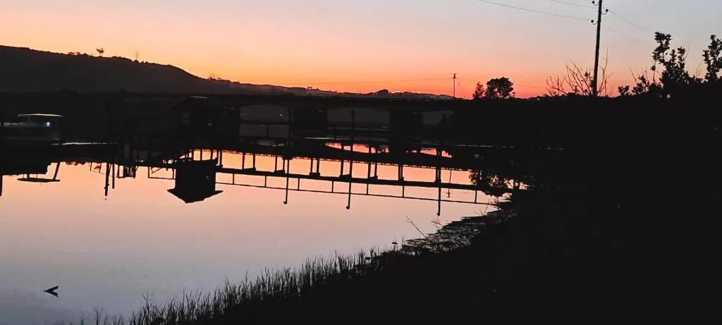 Serene sunset over Knysna lagoon with silhouetted structures and hills