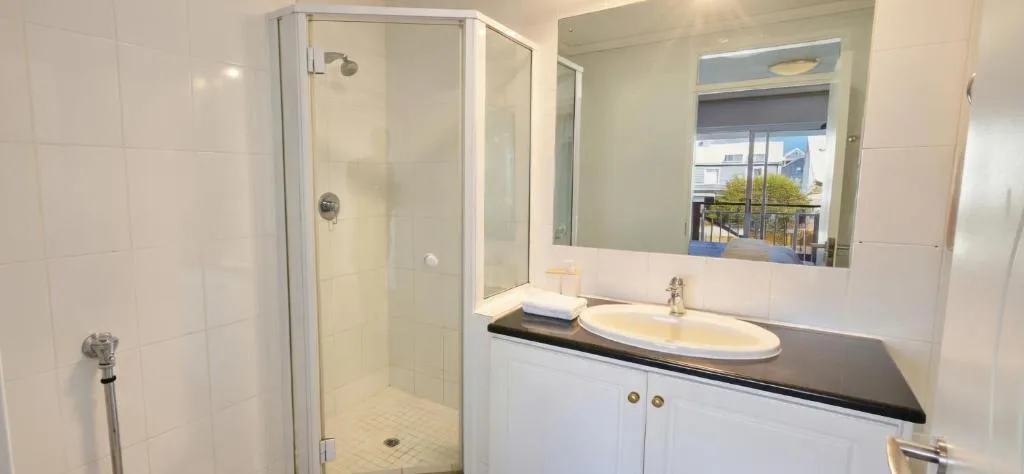 Modern bathroom with glass shower enclosure, white vanity, and large mirror