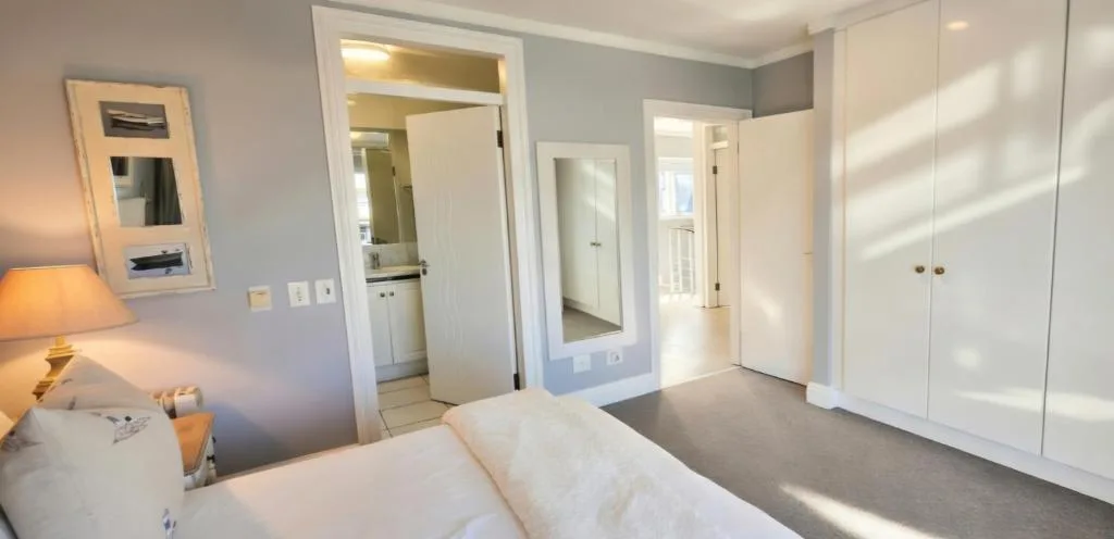Bright bedroom with double bed, ensuite bathroom, and white built-in wardrobes