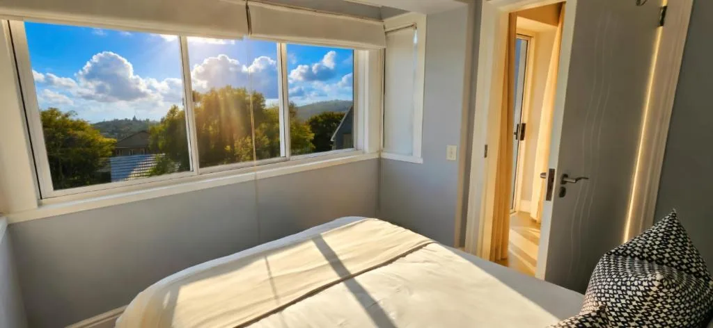 Bright bedroom with large windows overlooking mountain and garden views
