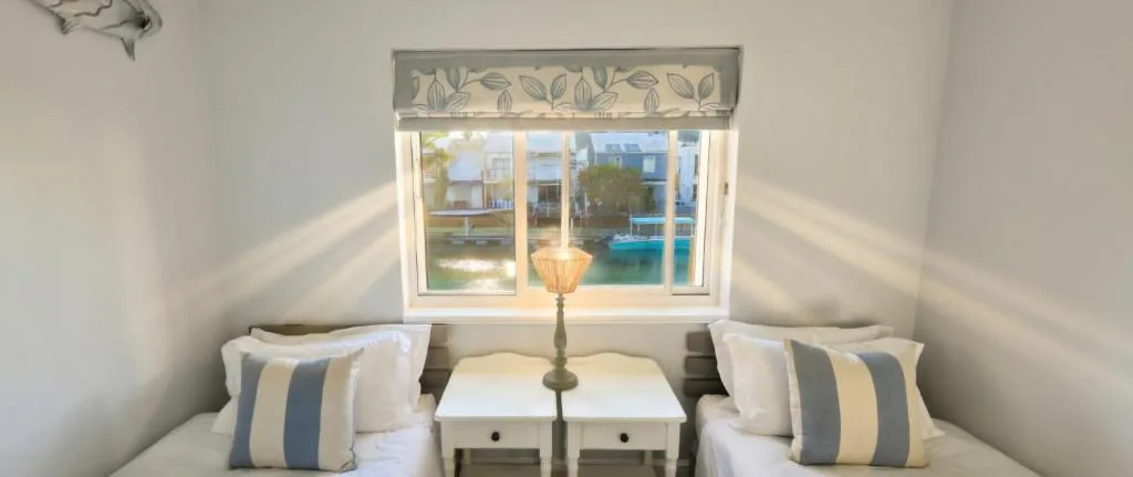 Twin beds with striped pillows overlooking Knysna waterfront view