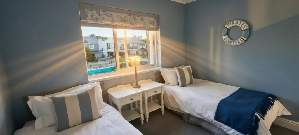 Twin bedroom with nautical decor and waterfront views through large window