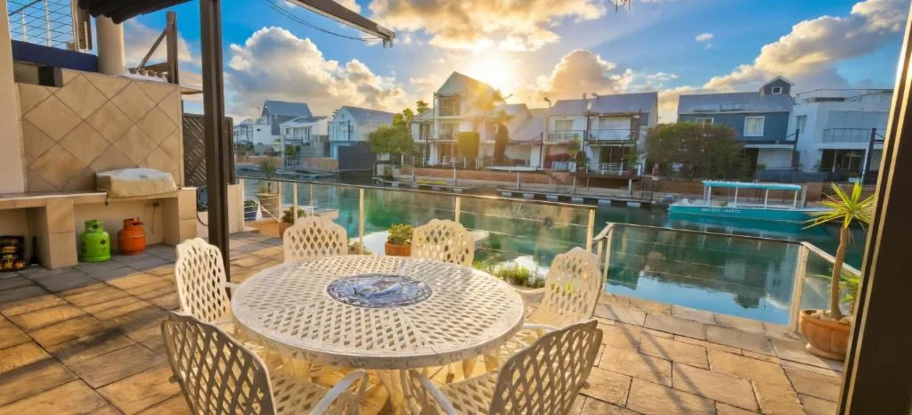 Waterfront patio with dining table overlooking Knysna lagoon and houses