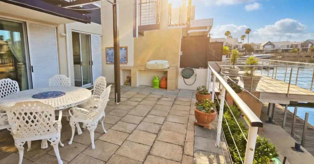Waterfront patio with white seating, potted plants, and lagoon views