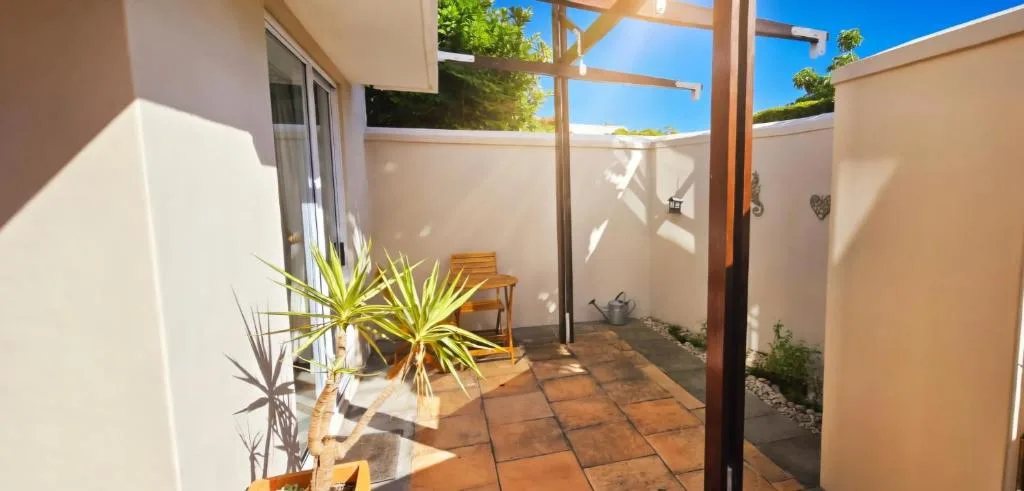Sunny courtyard patio with wooden pergola and potted plants