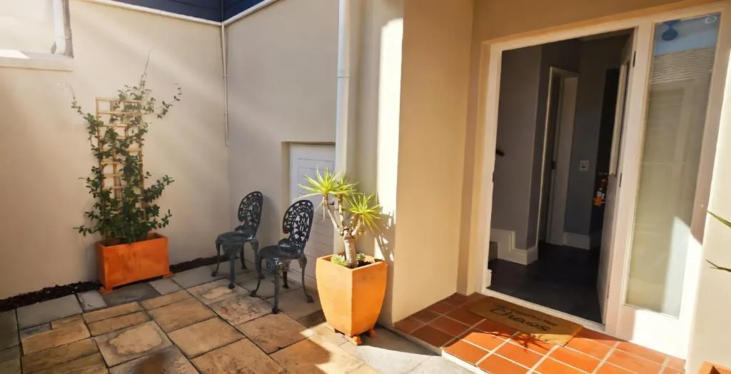 Bright courtyard with potted plants, decorative chairs, and tile flooring