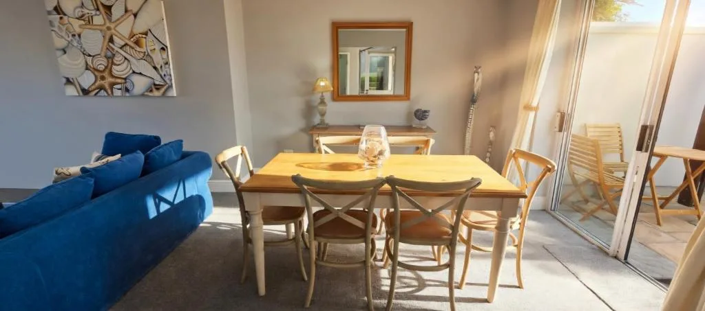 Bright dining area with wooden table and four chairs near blue lounge