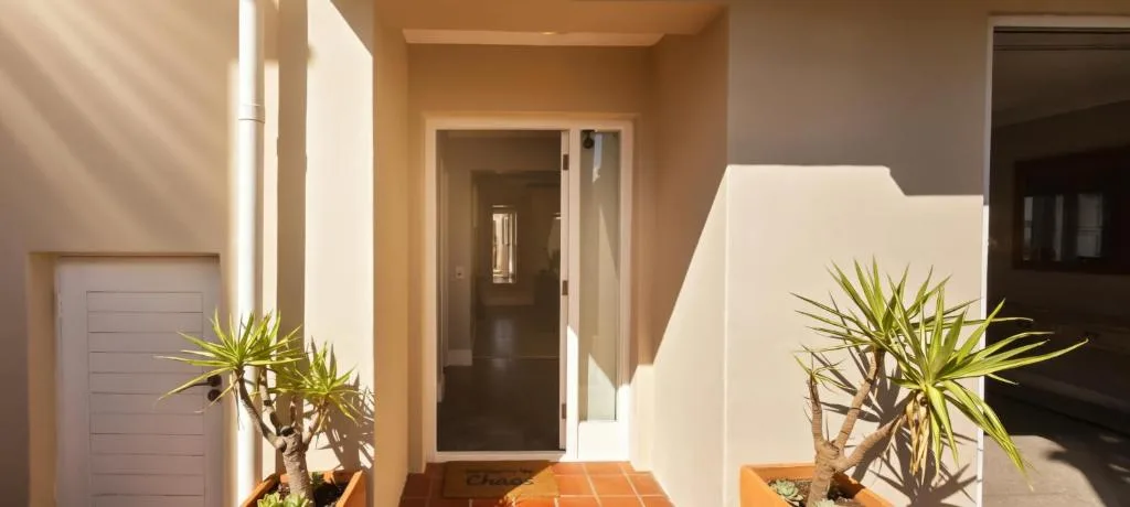 Modern entrance with white walls, terracotta tiles, and potted plants