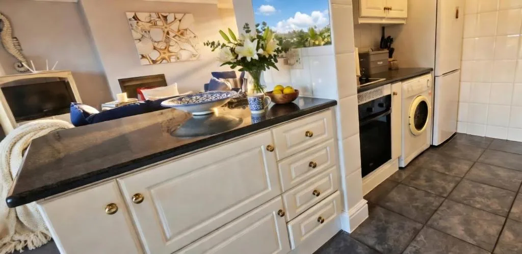 Modern kitchen with cream cabinetry, black countertops, and integrated appliances