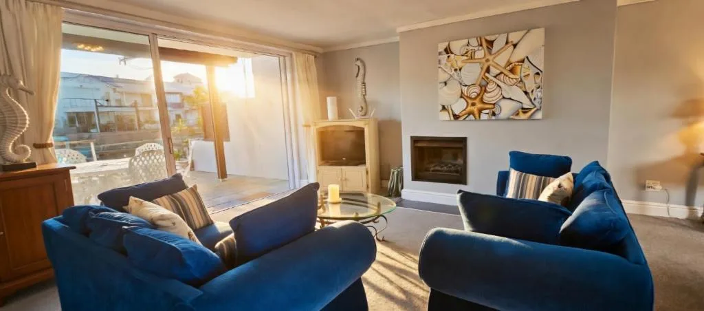 Spacious lounge with blue sofas, fireplace, and ocean views through glass doors