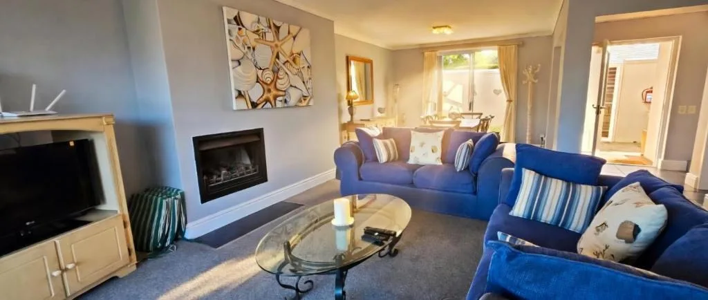 Spacious living room with blue sofas, fireplace, and bright windows