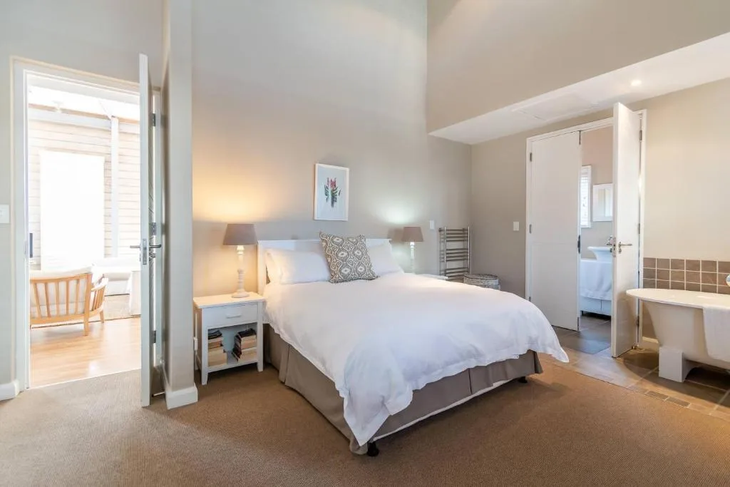 Spacious master bedroom with queen bed, bedside lamps, and en-suite bathroom access