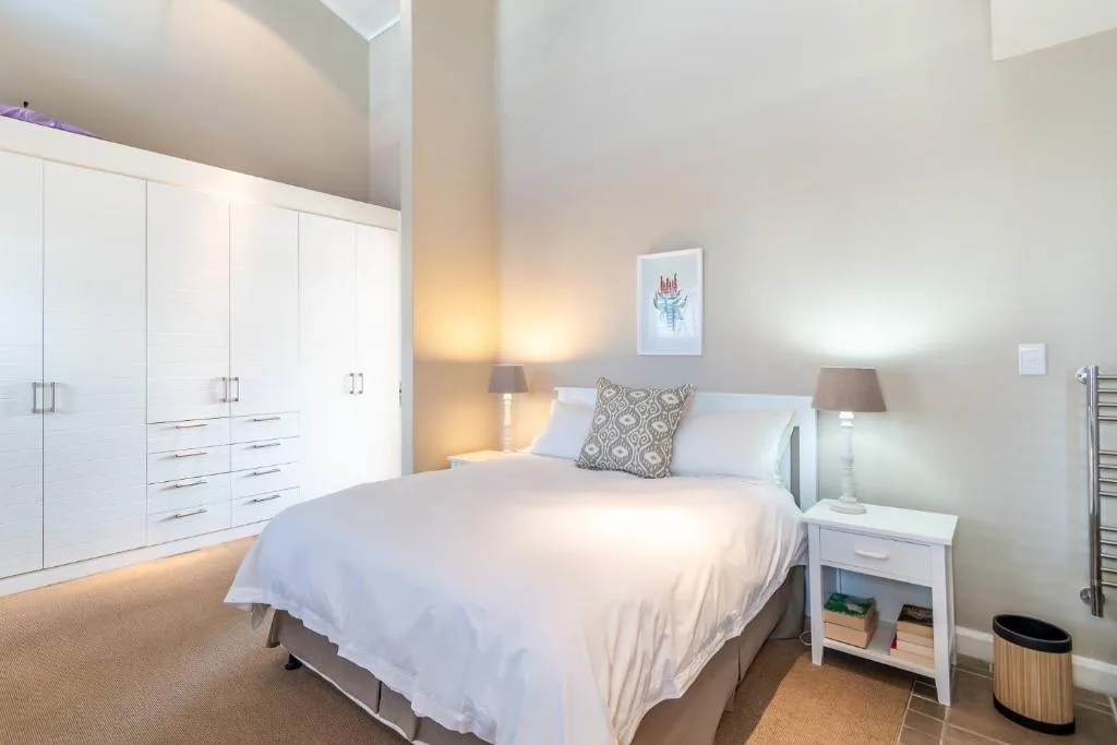 Modern bedroom with queen bed, white wardrobe, and bedside table lighting