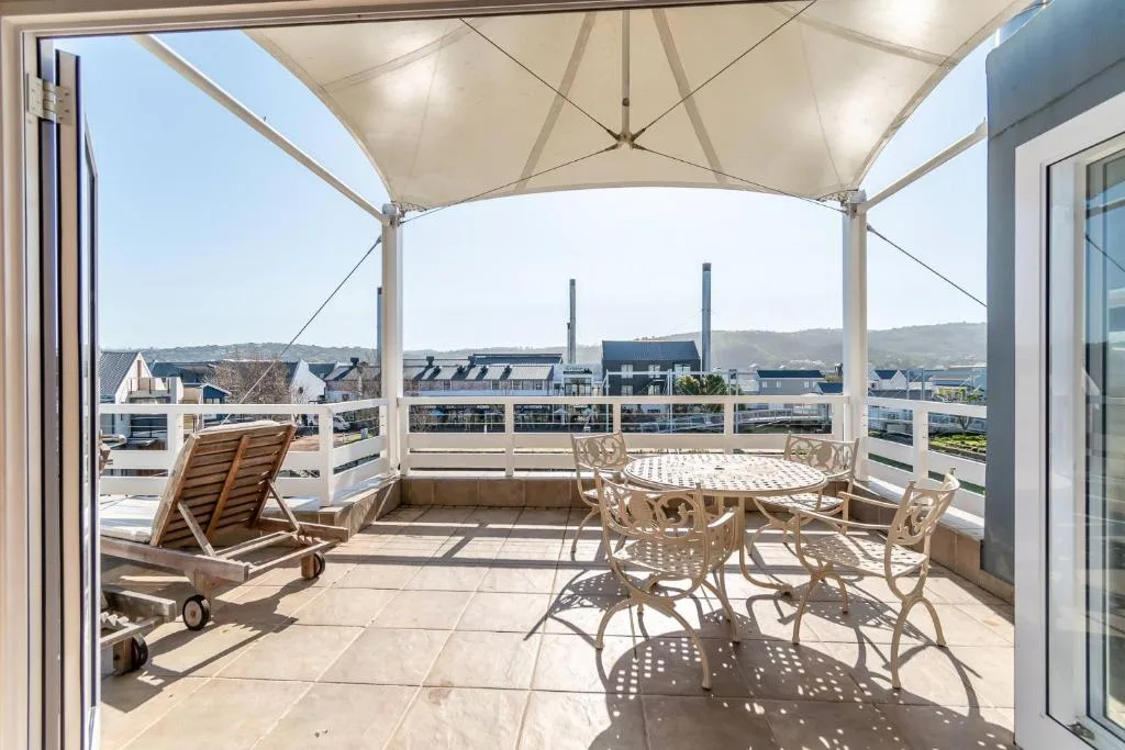 Shaded patio with loungers and dining furniture overlooking town