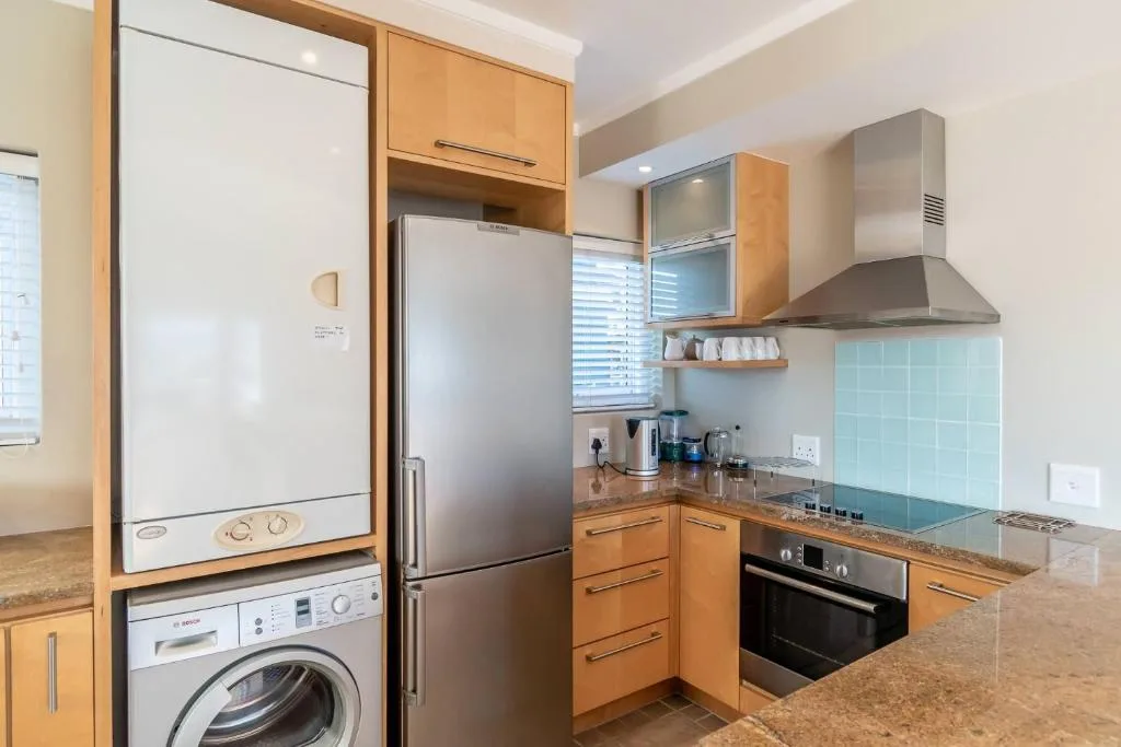 Modern kitchen with wooden cabinetry, stainless steel appliances, and turquoise backsplash