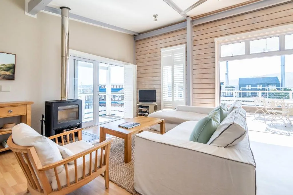 Spacious lounge with fireplace, sofas, and waterfront views through glass doors