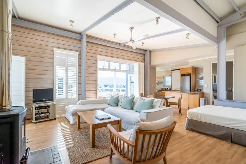 Spacious lounge with white sofa, wooden furniture, and ocean views through windows