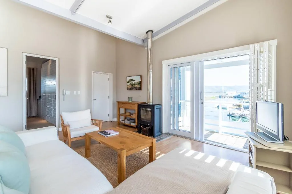 Bright lounge with wooden furniture and harbor view through glass doors