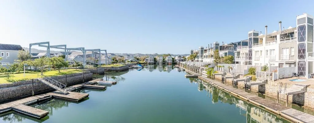 Scenic waterfront view of Knysna lagoon with modern residential buildings and boats