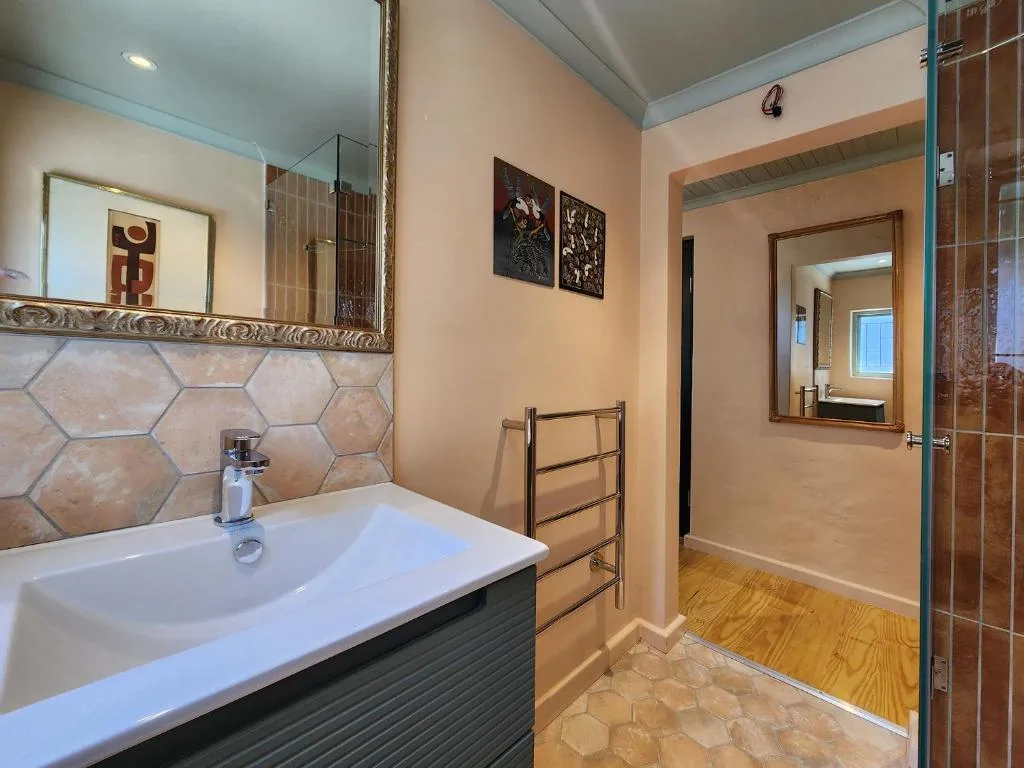 Modern bathroom with dual vanity, hexagonal tile backsplash, and walk-in shower