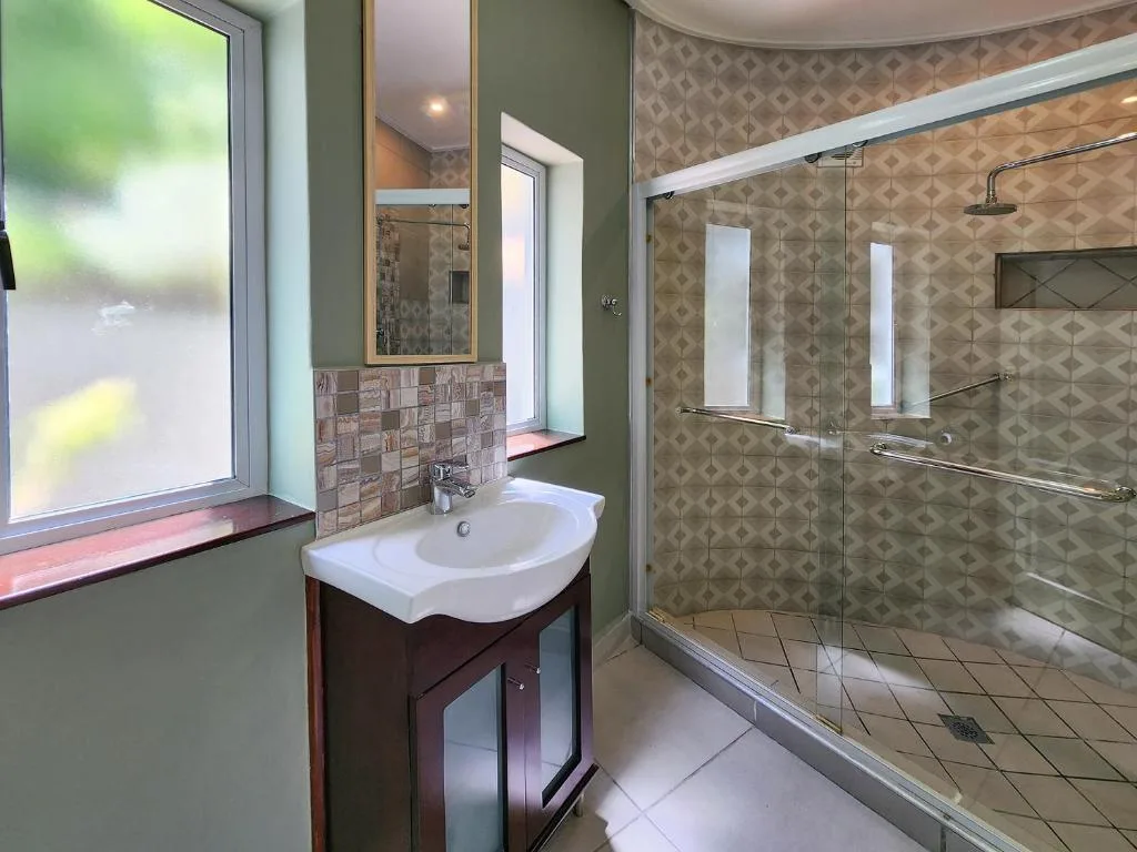 Modern bathroom with vanity sink, mirror, and frameless glass shower enclosure