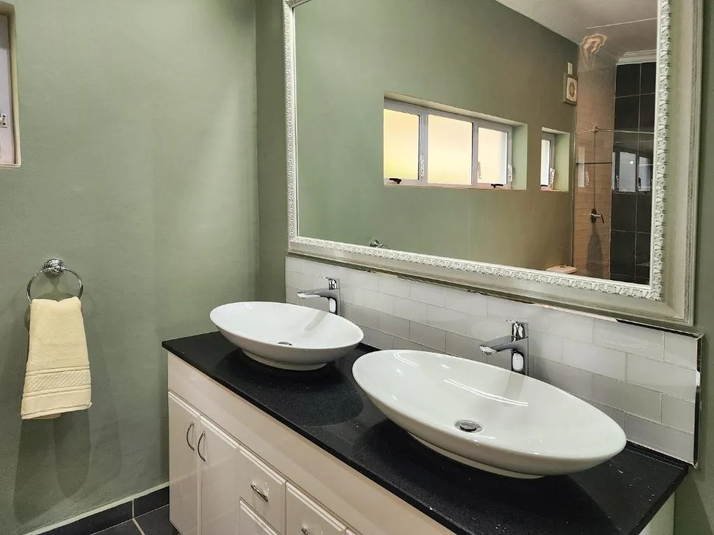 Modern bathroom with dual vessel sinks, black countertop, and large mirror