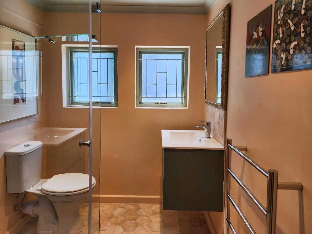 Modern bathroom with shower, toilet, sink vanity, and large windows
