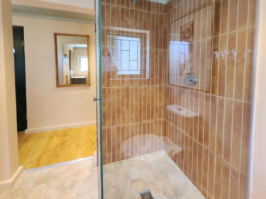 Modern walk-in shower with terracotta tiles and glass enclosure doors
