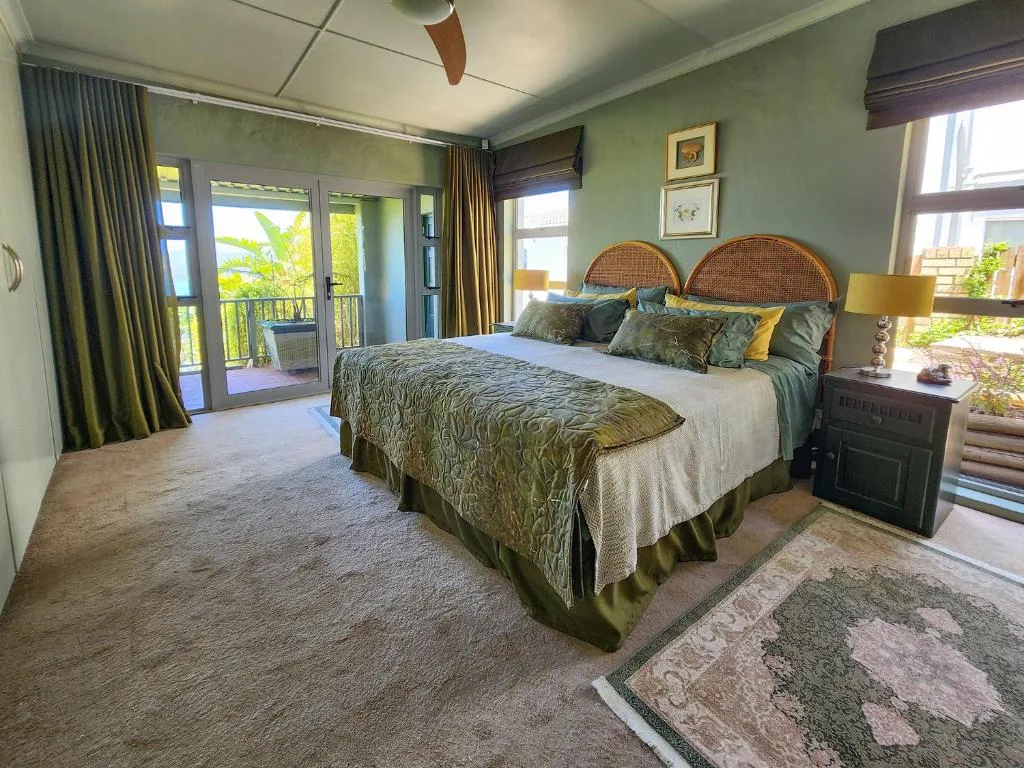 Spacious bedroom with queen bed, rattan headboard, and deck access with garden views