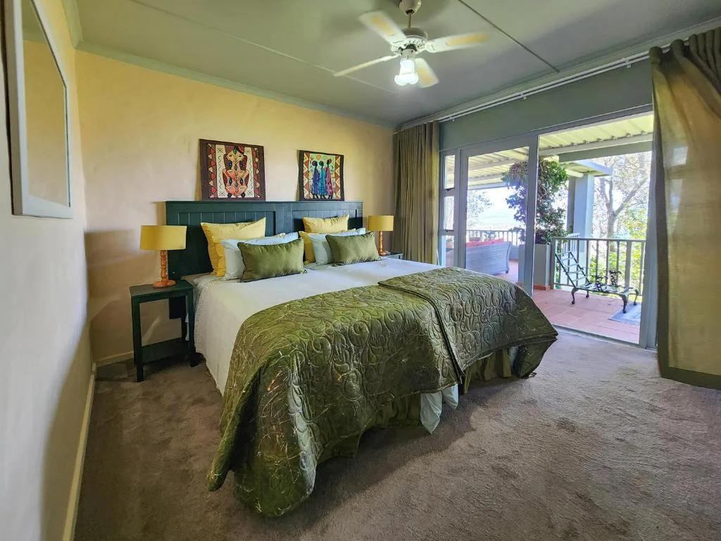 Spacious bedroom with queen bed, green upholstered headboard, and deck access