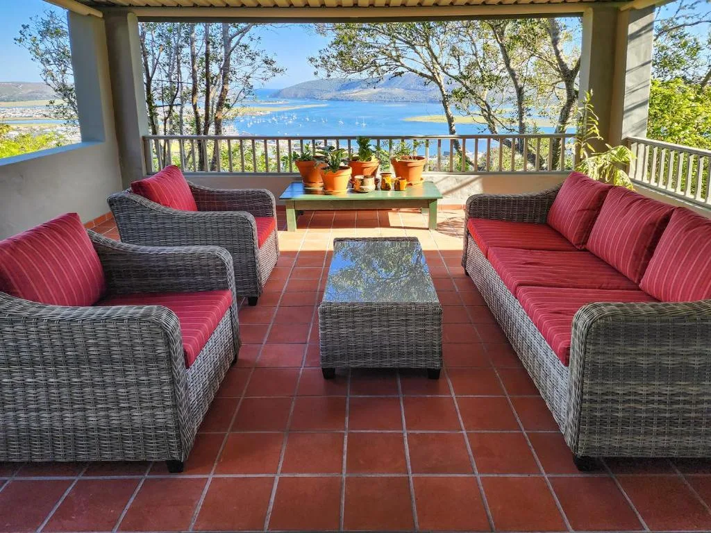 Covered patio with wicker seating and lagoon views beyond railing