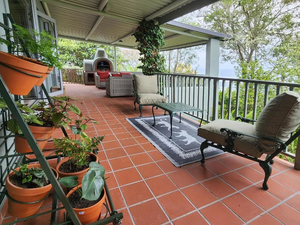 Covered terrace with comfortable seating, potted plants, and brick pizza oven