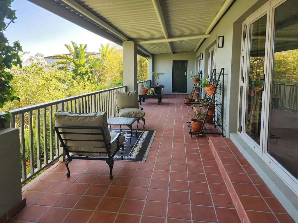 Spacious covered patio with comfortable seating and potted plants overlooking gardens