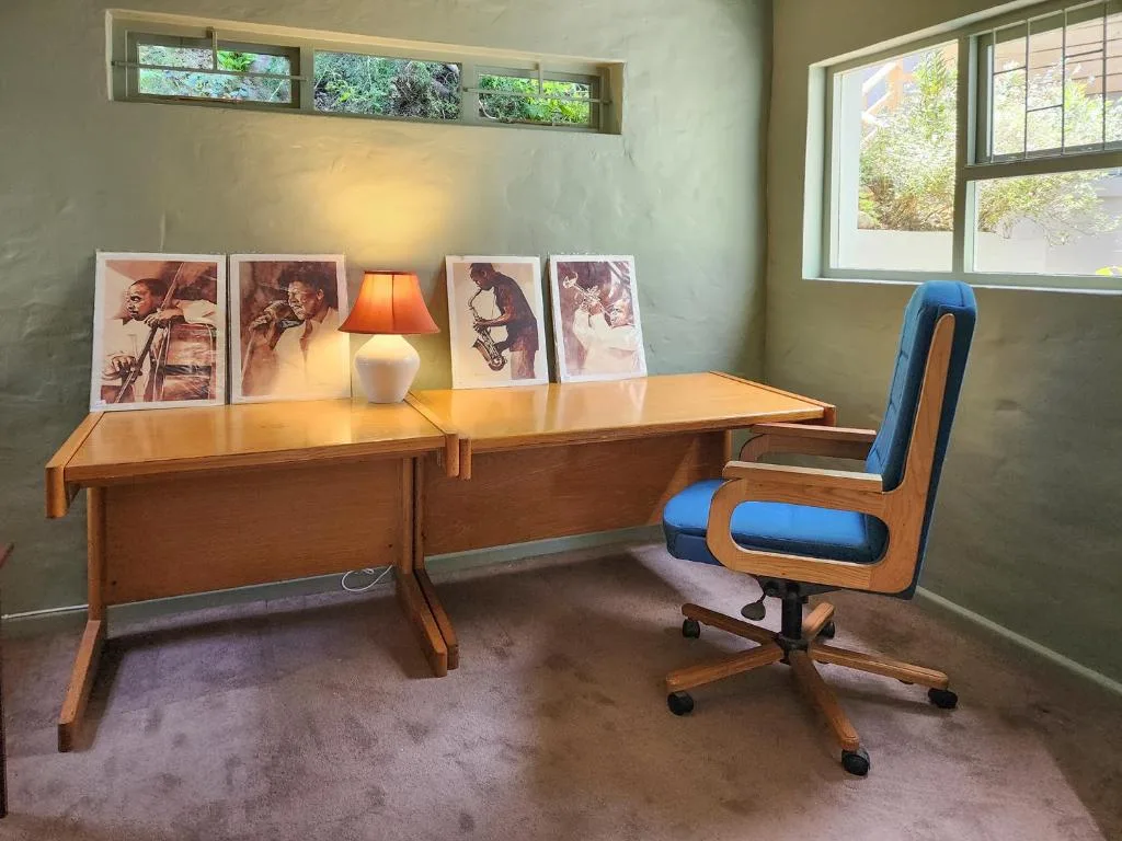 Mid-century wooden desk with blue chair and vintage artwork display