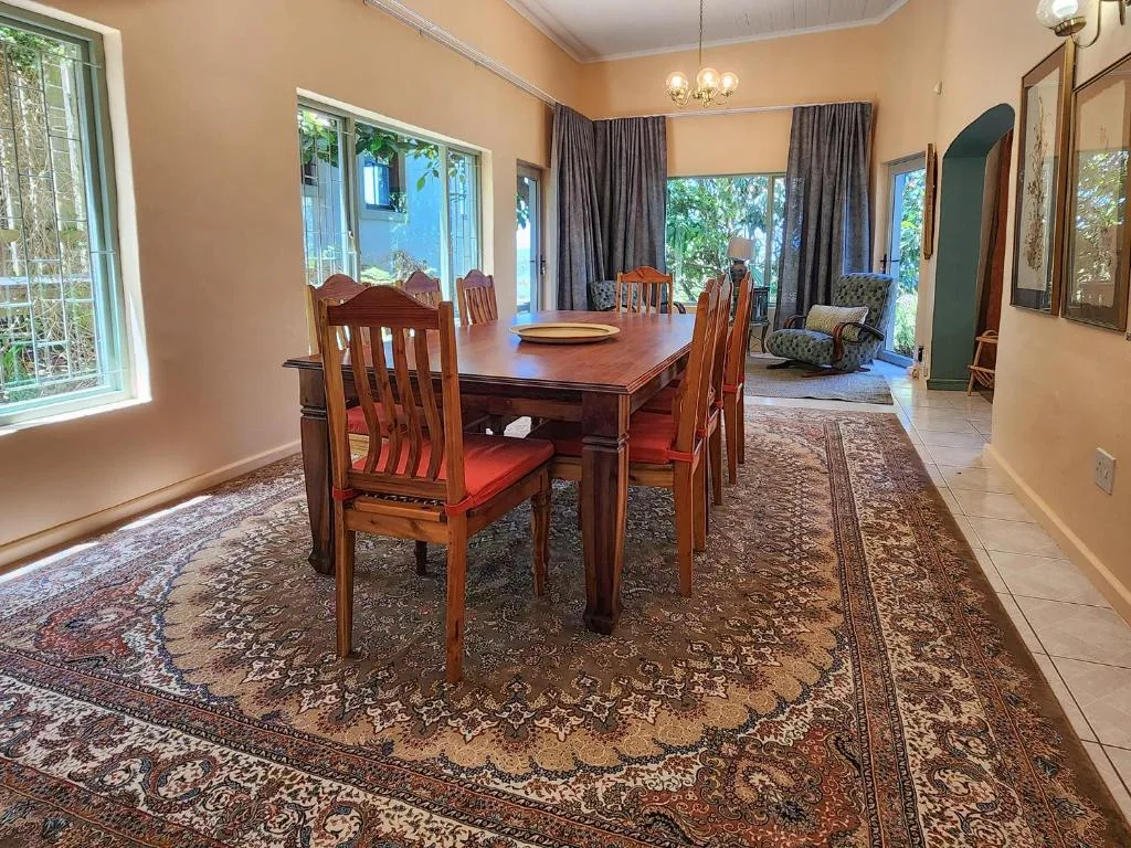 Spacious dining room with wooden table, red cushioned chairs, and garden views