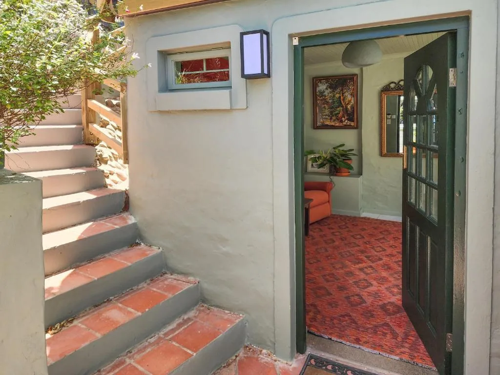 Entrance to villa with terracotta steps, green door, and climbing ivy