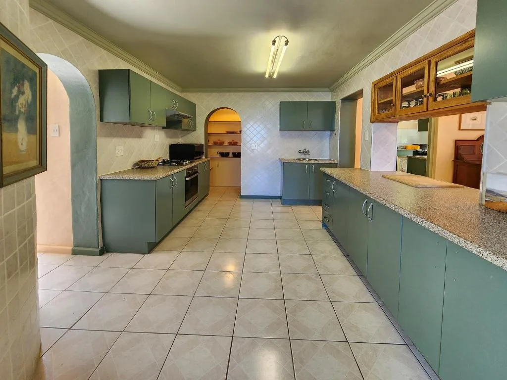Spacious kitchen with sage green cabinetry, granite countertops, and tiled flooring