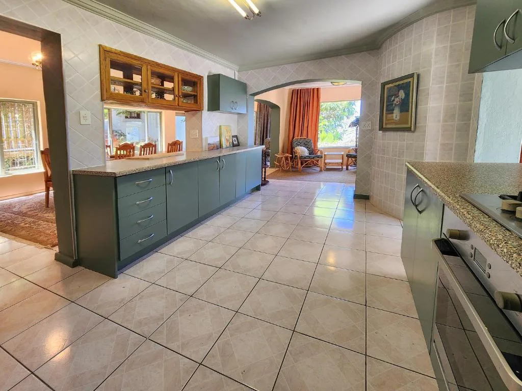 Spacious kitchen with green cabinetry, granite countertops, and tiled flooring
