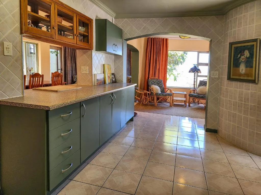 Open-plan kitchen with green cabinetry, granite countertop, and lounge area beyond